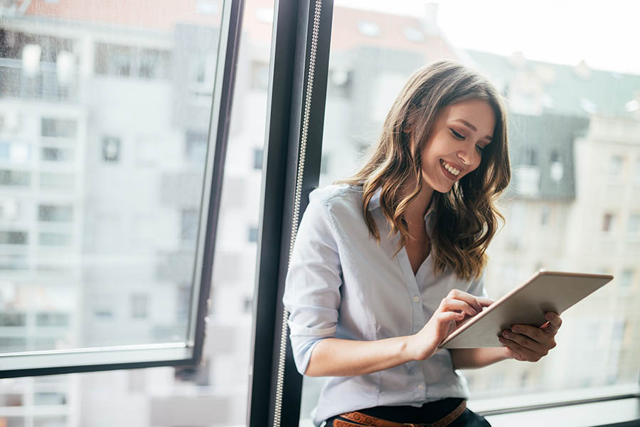 Client Center - Young Woman Using Tablet in the Office With Cityscape in the Background