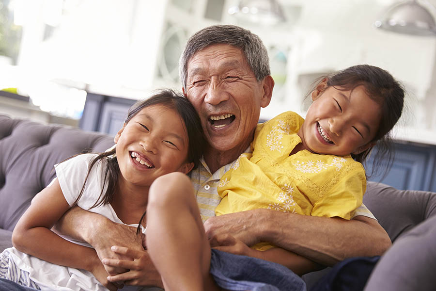 Personal Insurance - Grandfather and Granddaughters Relaxing on Sofa at Home